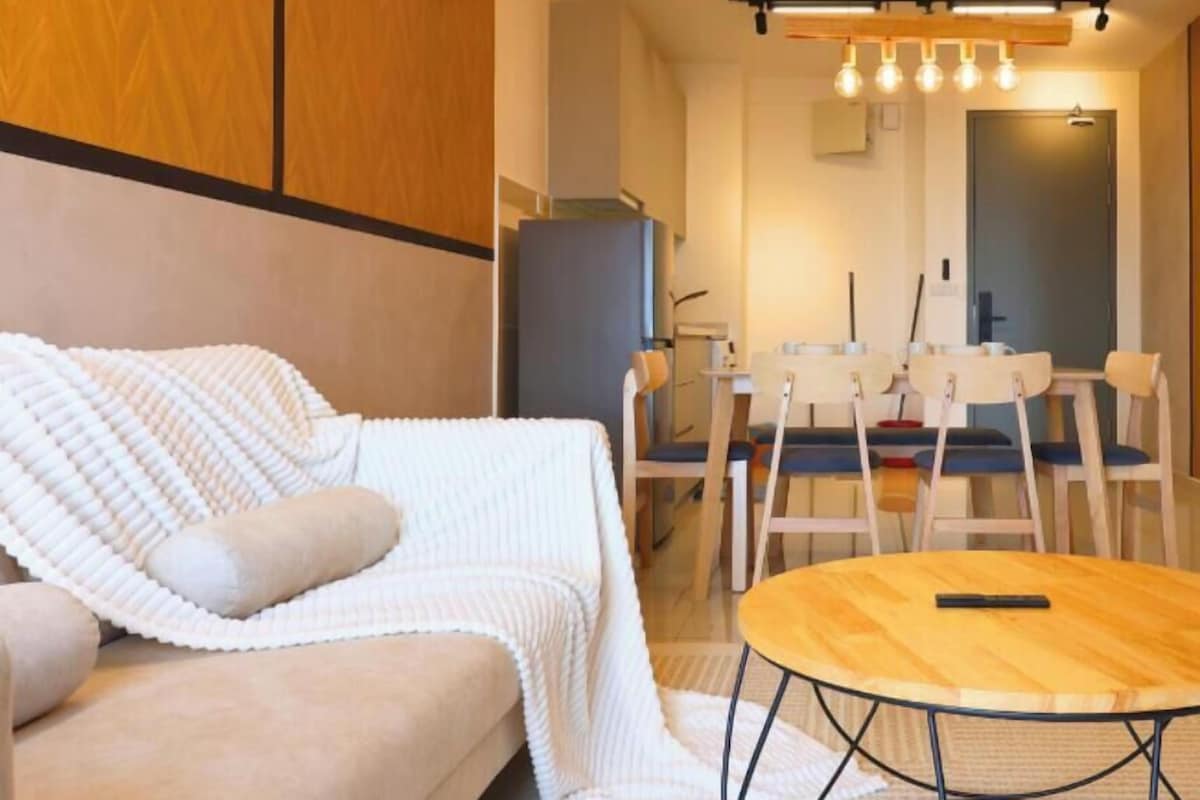 Ein modernes Wohnzimmer mit einer Couch, einem runden Couchtisch und einem Essbereich mit Stühlen und einem Tisch.
