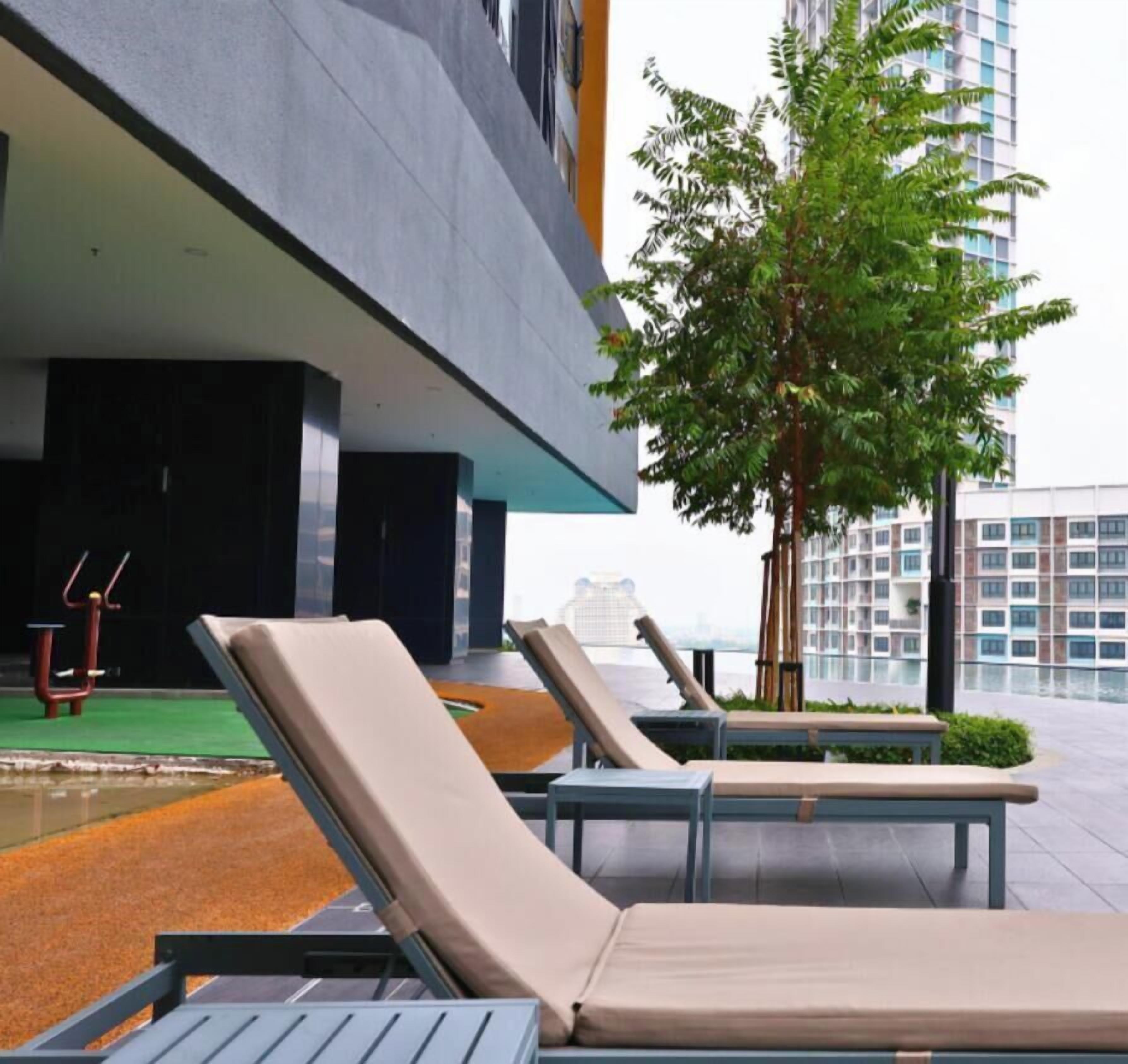A rooftop lounge area with sun loungers, a small exercise area, and a tree.