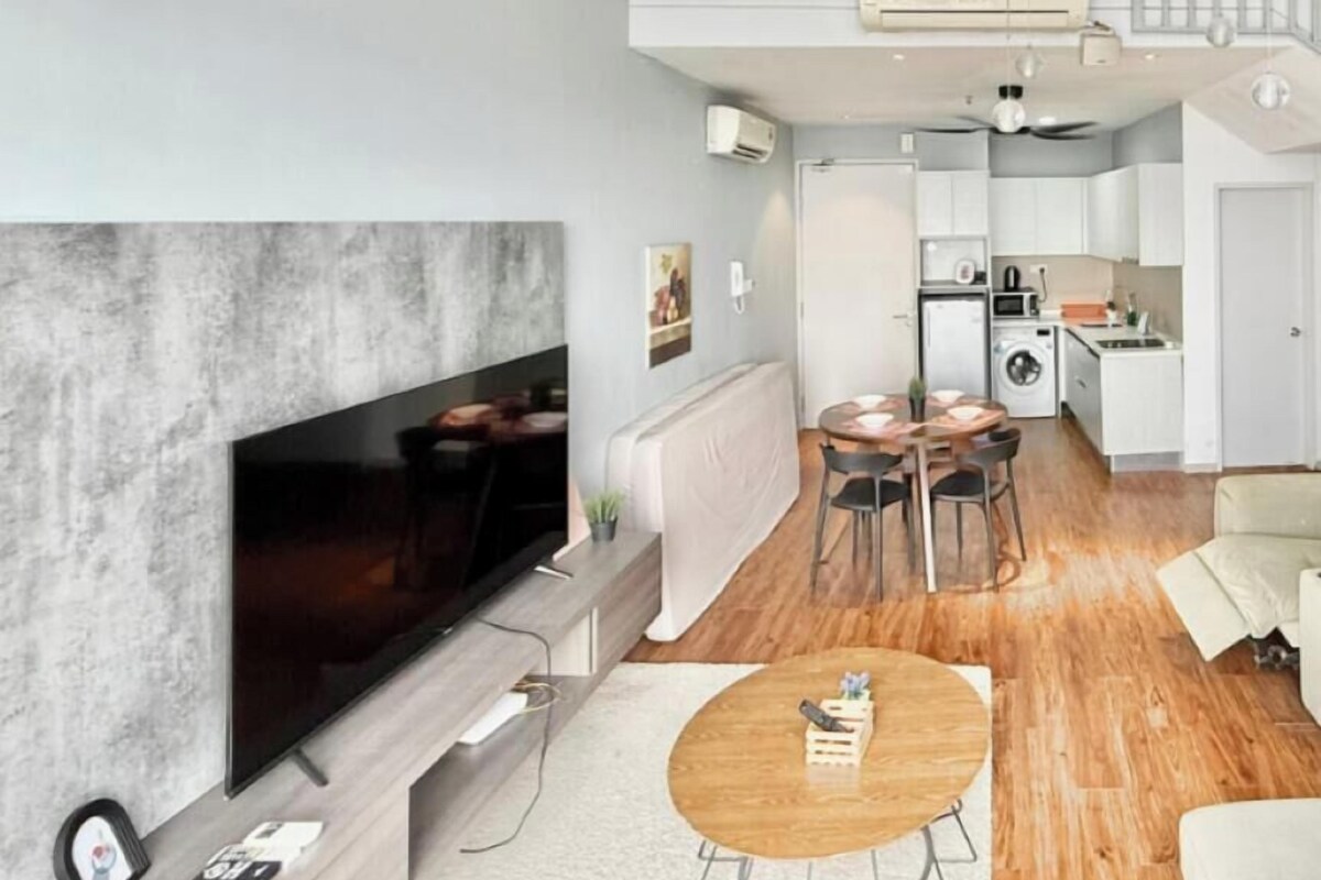 Ein modernes Wohnzimmer mit Flachbildfernseher, ein Essbereich mit rundem Tisch und eine Küche mit Einbauofen und Mikrowelle.