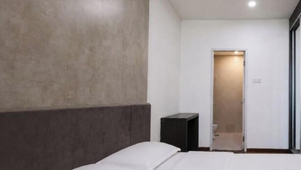 A hotel room with a bed, a bedside table, and a door leading to a bathroom. - I-City Shah Alam Residences By Asdeh (Shah Alam)