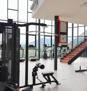 A gym with exercise equipment, a staircase, and large windows.