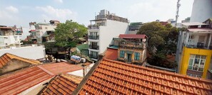 Un toit recouvert de tuiles en terre cuite, un arbre et des bâtiments dotés de balcons et de fenêtres.