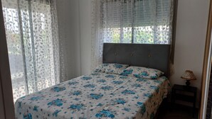 Ein Schlafzimmer mit einem Bett, einem Nachttisch und einem Fenster mit Vorhängen.