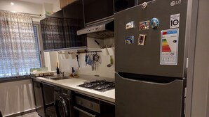 Eine kompakte Küche mit einem Edelstahl-Kühlschrank, einem Gasherd, einem Backofen und einer Waschmaschine.