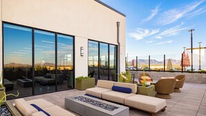 A modern outdoor seating area with a fire pit, sofas, and chairs, overlooking a desert landscape.
