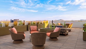 Una terraza en la azotea con mobiliario de mimbre, plantas en macetas y vistas a las montañas.