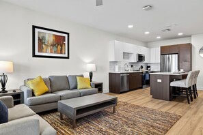 A modern living room with a grey sofa, a coffee table, and a colorful rug. - Rooftop Pool + Gym + Sauna | Near TPC Golf + Preserve | Azur by AvantStay (Phoenix)