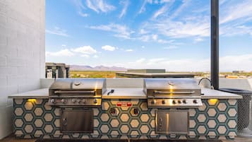An outdoor grill station with two gas grills, a built-in cooler, and a view of the desert landscape.