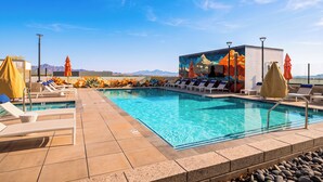 A pool area with lounge chairs, umbrellas, and a mural on the wall.