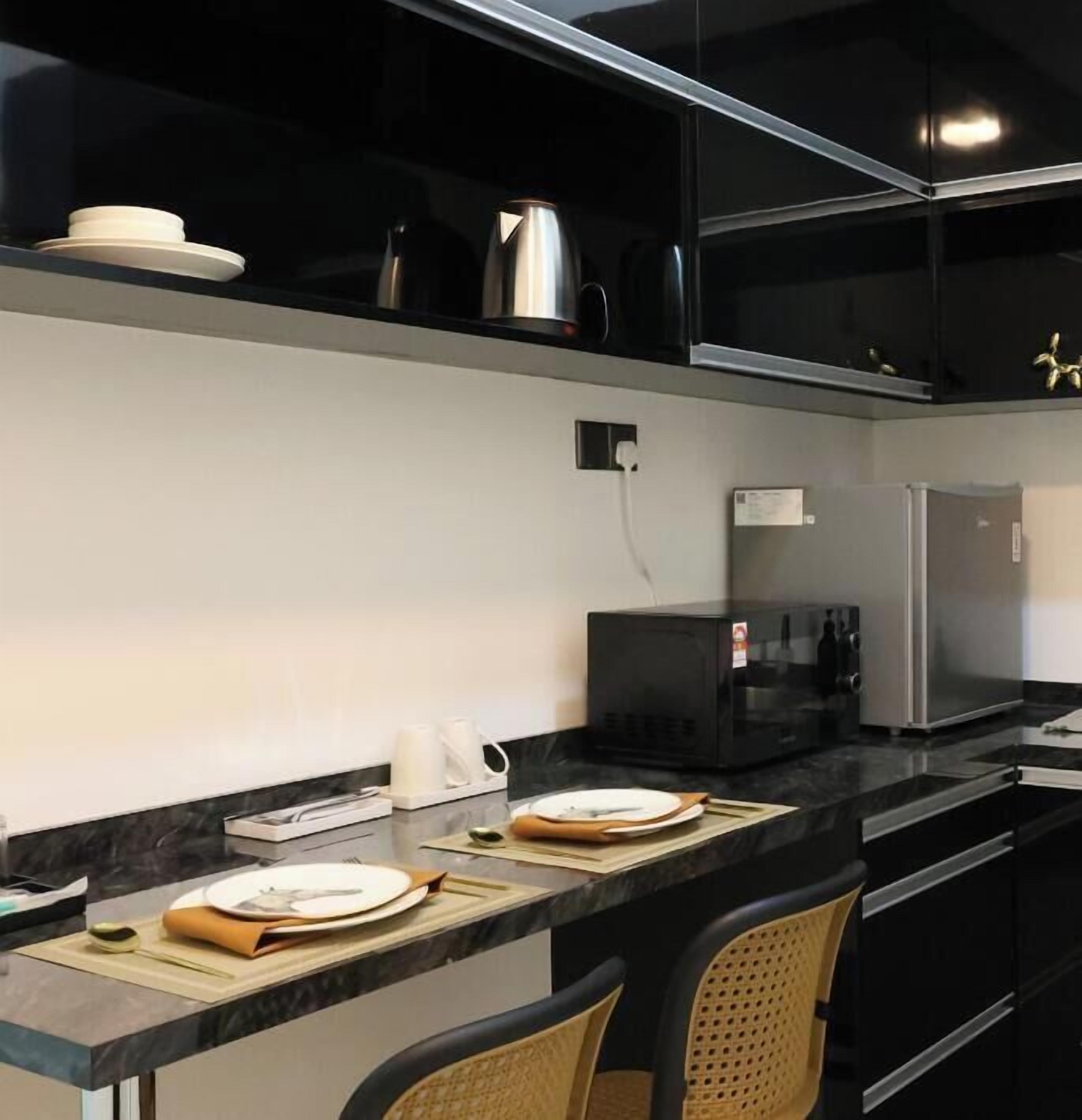 A modern kitchen with a black countertop, stainless steel appliances, and a microwave.