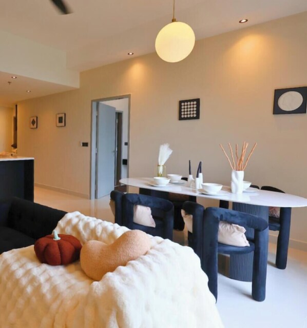 A modern dining area with a round table, dark chairs, and a white tablecloth. - Novo Ampang Suites By Asdeh (KL)