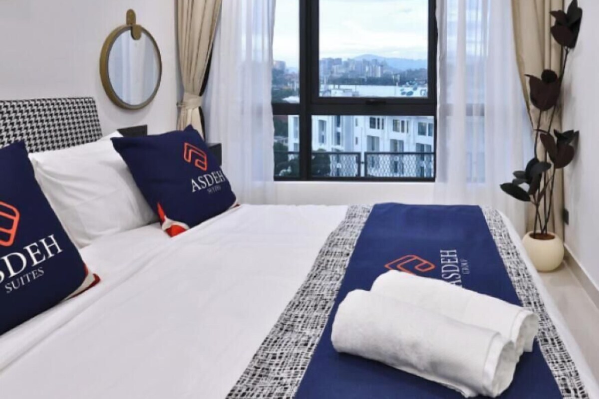 A hotel room with a large bed, a view of the city, and a window with curtains.
