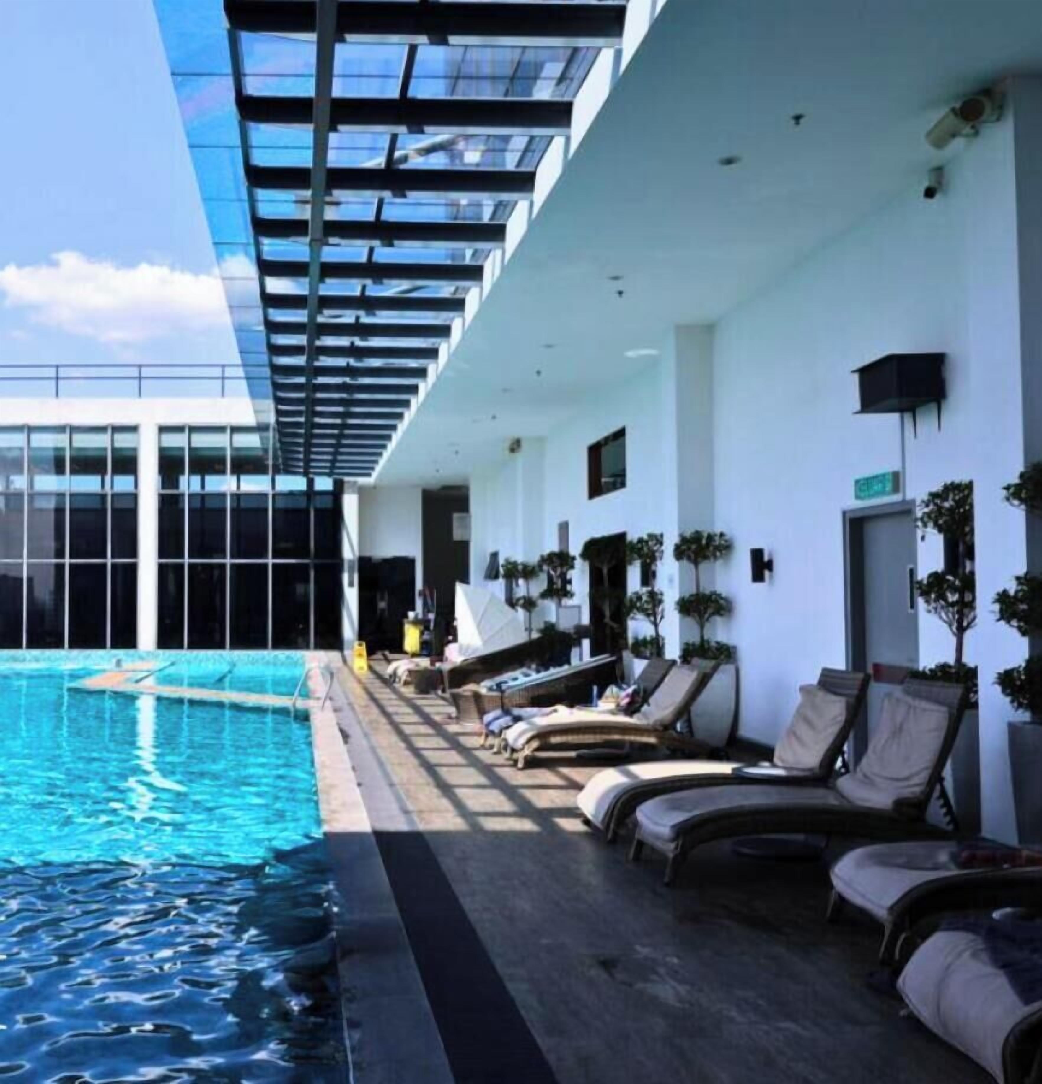Un espace piscine intérieur moderne, doté de chaises longues et de plantes en pot.