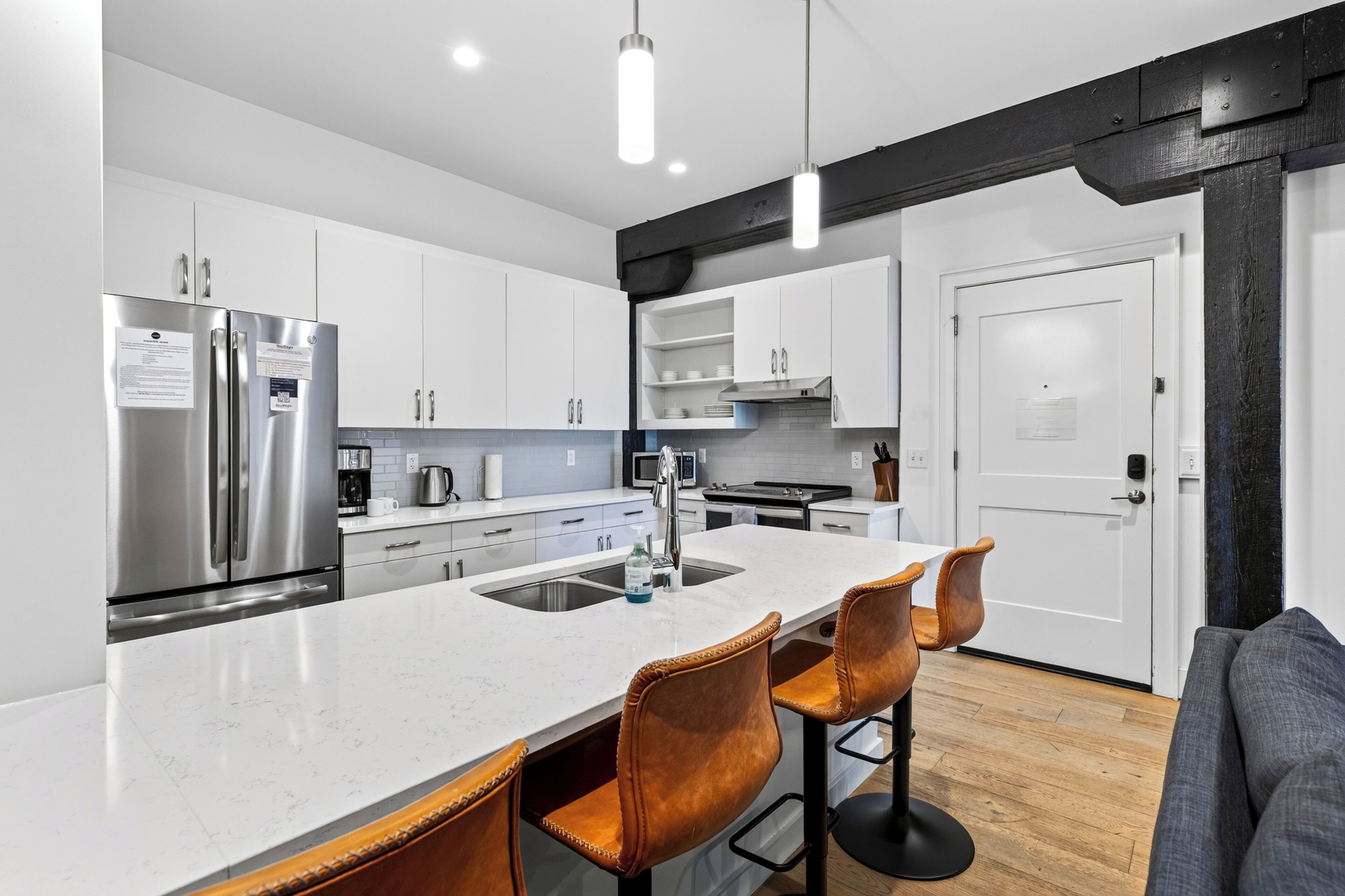 Una cocina moderna con una isla central, electrodomésticos de acero inoxidable y una puerta con marco negro.