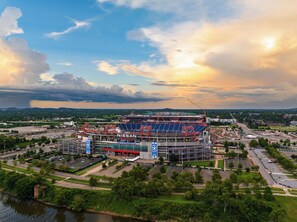 A stadium with a large seating area, a parking lot, and a river in the foreground. - Brick + Full Kitchen | Half Block to Lower Broadway | Spotlight by AvantStay (Nashville)