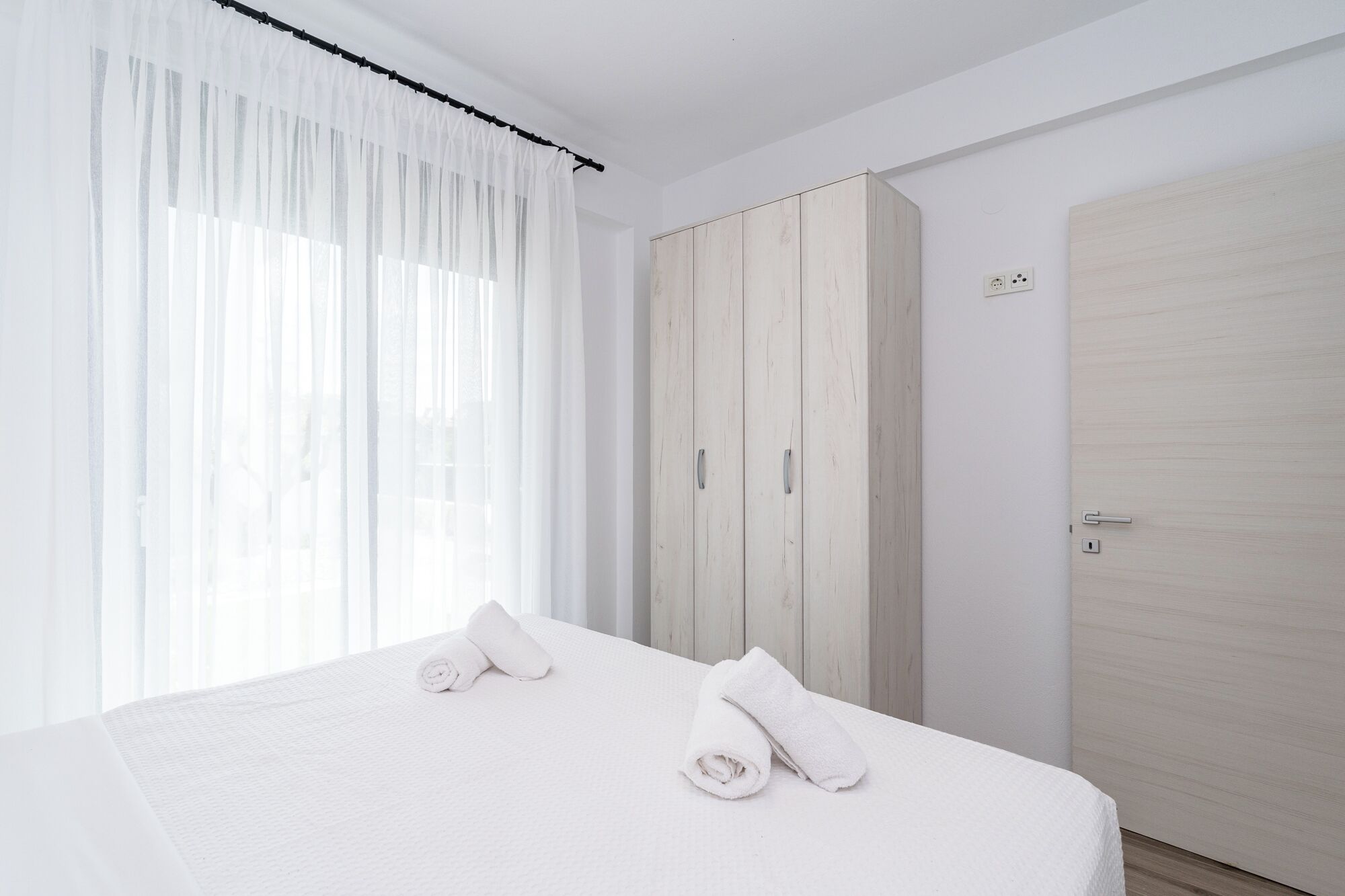 A hotel room with a bed, a wardrobe, and a door.