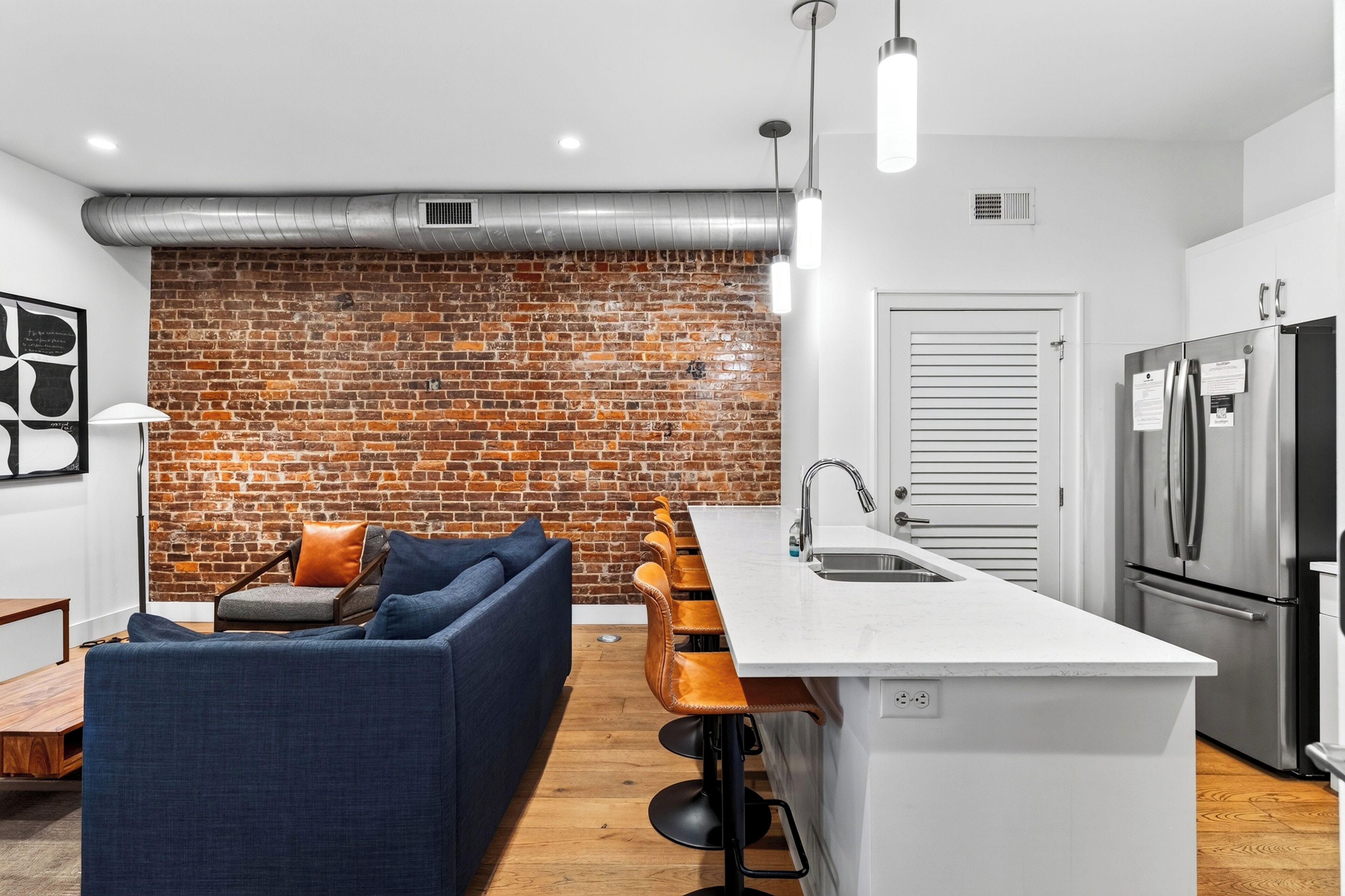 A modern kitchen with a brick wall, a sofa, and a bar area.