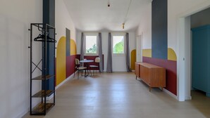 Ein Korridor mit Holzboden, einem Metallgestell, einem Tisch mit Stühlen und einem Schrank.