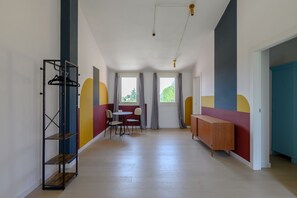 A hallway with a wooden floor, a metal rack, a table with chairs, and a cabinet. - GuestHost - Kidane Apartment Padova (Padua)
