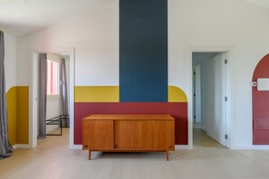 A room with a wooden cabinet, a door, and a wall with a geometric design. - GuestHost - Kidane Apartment Padova (Padua)