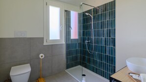 Ein Badezimmer mit Toilette, einer Dusche mit Glastür und einem Waschbecken.