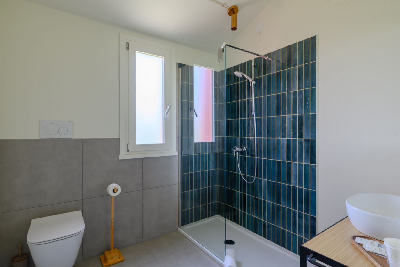A bathroom with a toilet, a shower with a glass door, and a sink with a bowl.