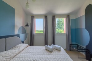 A bedroom with a bed, two windows, a bedside table, a lamp, and a wall-mounted shelf. - GuestHost - Kidane Apartment Padova (Padua)