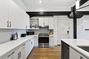 Eine moderne Küche mit weißen Schränken, Edelstahlgeräten und Holzboden.
