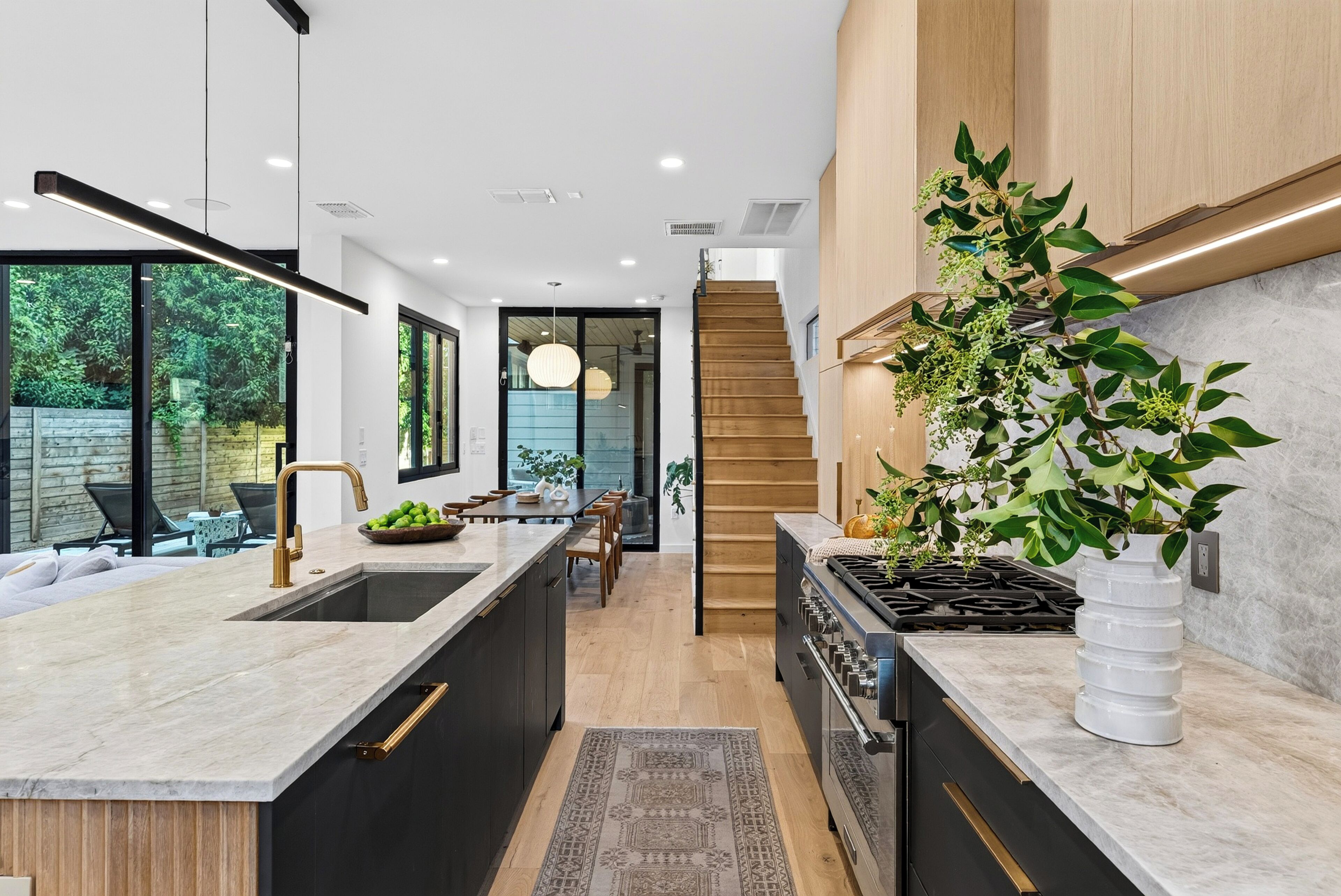 Una cocina moderna con una isla central, estufa integrada y un amplio ventanal con vistas a un jardín.