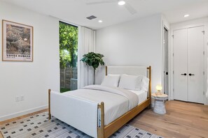 Una camera da letto moderna con un letto, una pianta in vaso, una lampada da comodino e una porta.