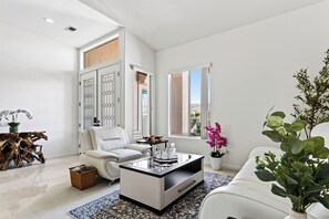 A modern living room with a white sofa, a coffee table, and a large window. - Golf Views + BBQ Patio | Mins to Indian Wells | Palm & Par (Palm Desert)