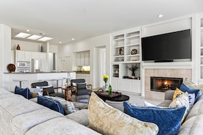 A modern living room with a large flat-screen TV, a fireplace, and a cozy seating area. - Golf Views + BBQ Patio | Mins to Indian Wells | Palm & Par (Palm Desert)