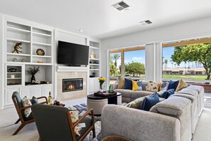 A modern living room with a fireplace, a large flat-screen TV, and a sofa set. - Golf Views + BBQ Patio | Mins to Indian Wells | Palm & Par (Palm Desert)
