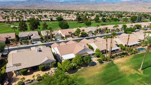 Zona residencial amb cases, un camp de golf i muntanyes al fons.