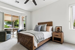 Une chambre à coucher avec un lit en bois, une table de chevet, une chaise et une grande fenêtre.