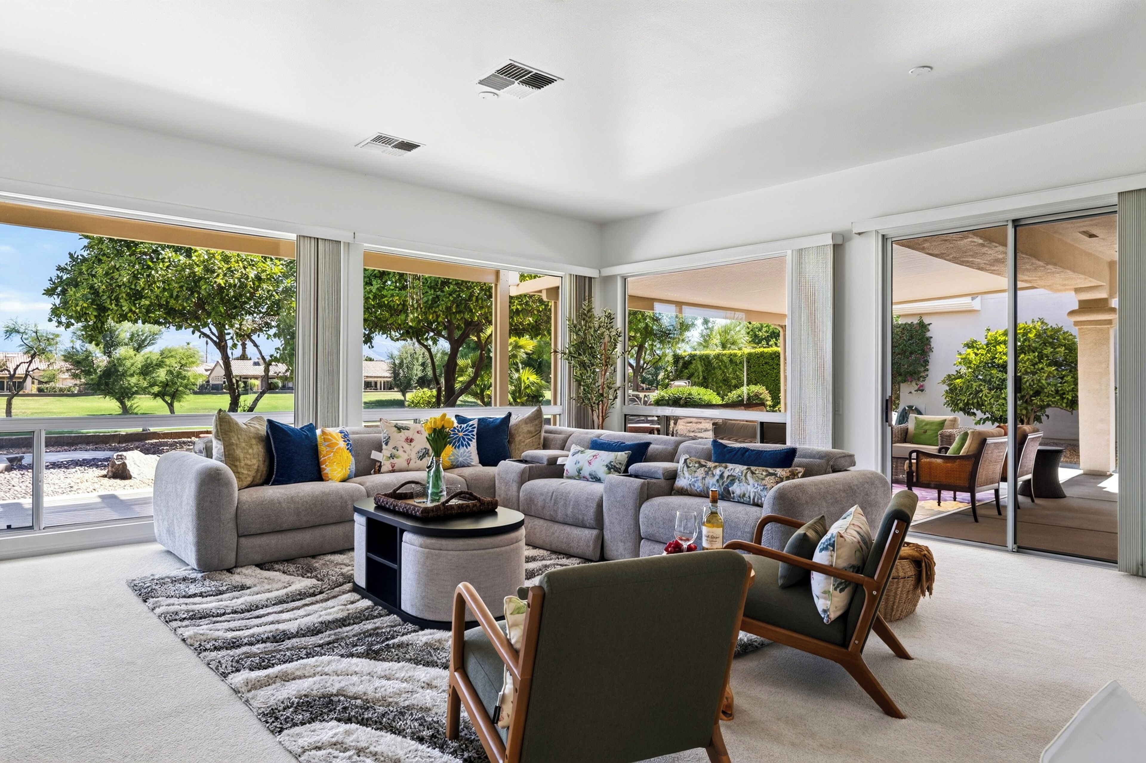 A spacious living area with a large sofa set, a coffee table, and a dining area with chairs.