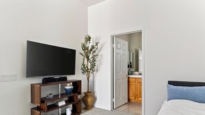 Un dormitori amb televisió, una planta i una porta que dóna al bany.