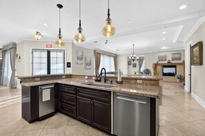 A spacious kitchen with dark cabinetry, a built-in dishwasher, and a granite countertop. - 20 Acres • Lake + Pool + Spa • Near Hard Rock Casino | Vista del Lago Estate (Bakersfield)