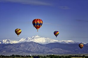 A landscape with four hot air balloons flying over a snow-capped mountain range.