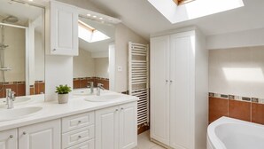 A modern bathroom with skylights, a walk-in shower, and a large bathtub.
