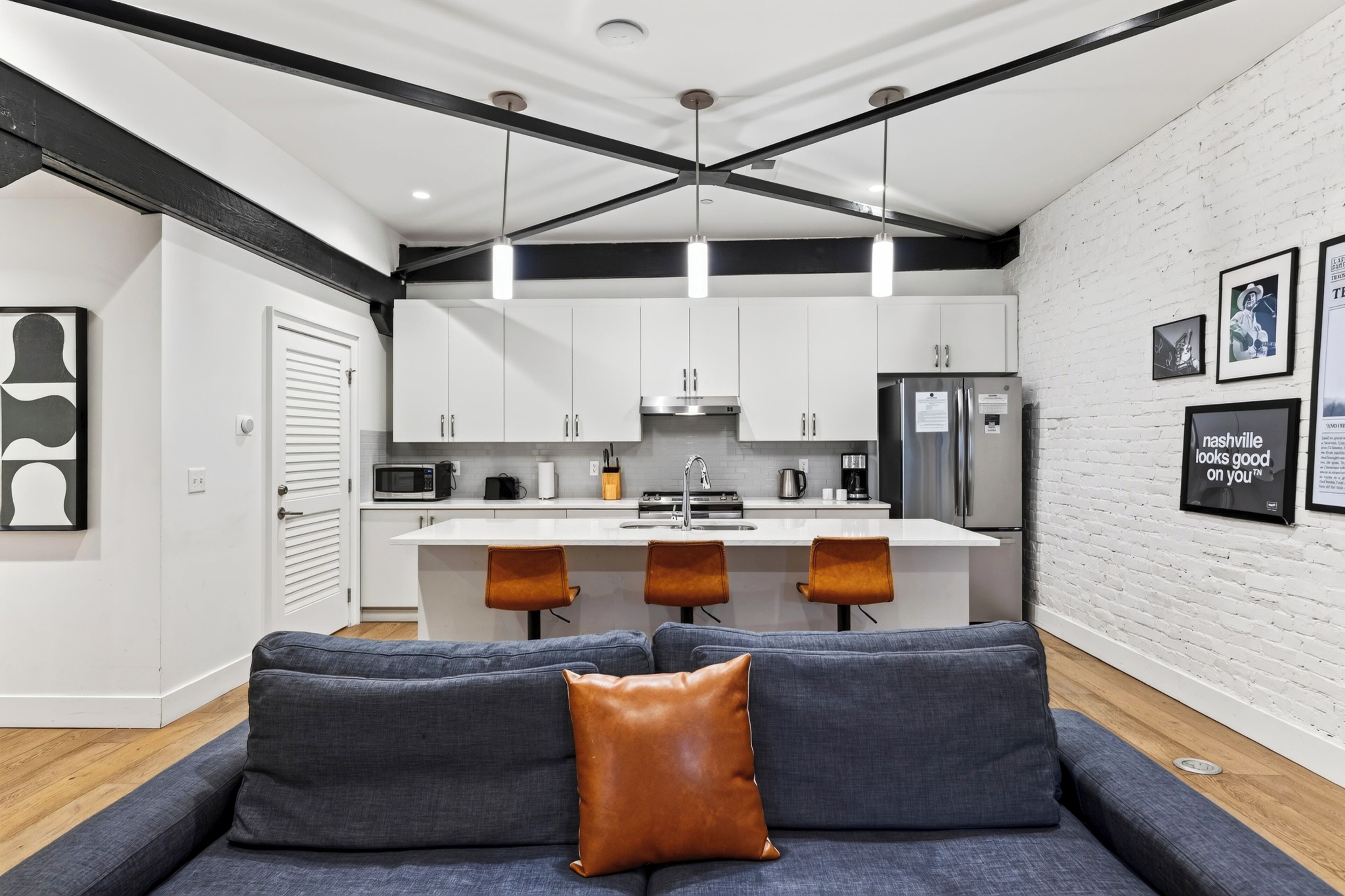 A modern kitchen with white cabinets, a central island, and bar stools.