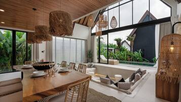 Comedor con una mesa de madera, sillas de mimbre y un amplio ventanal con vistas a un jardín.
