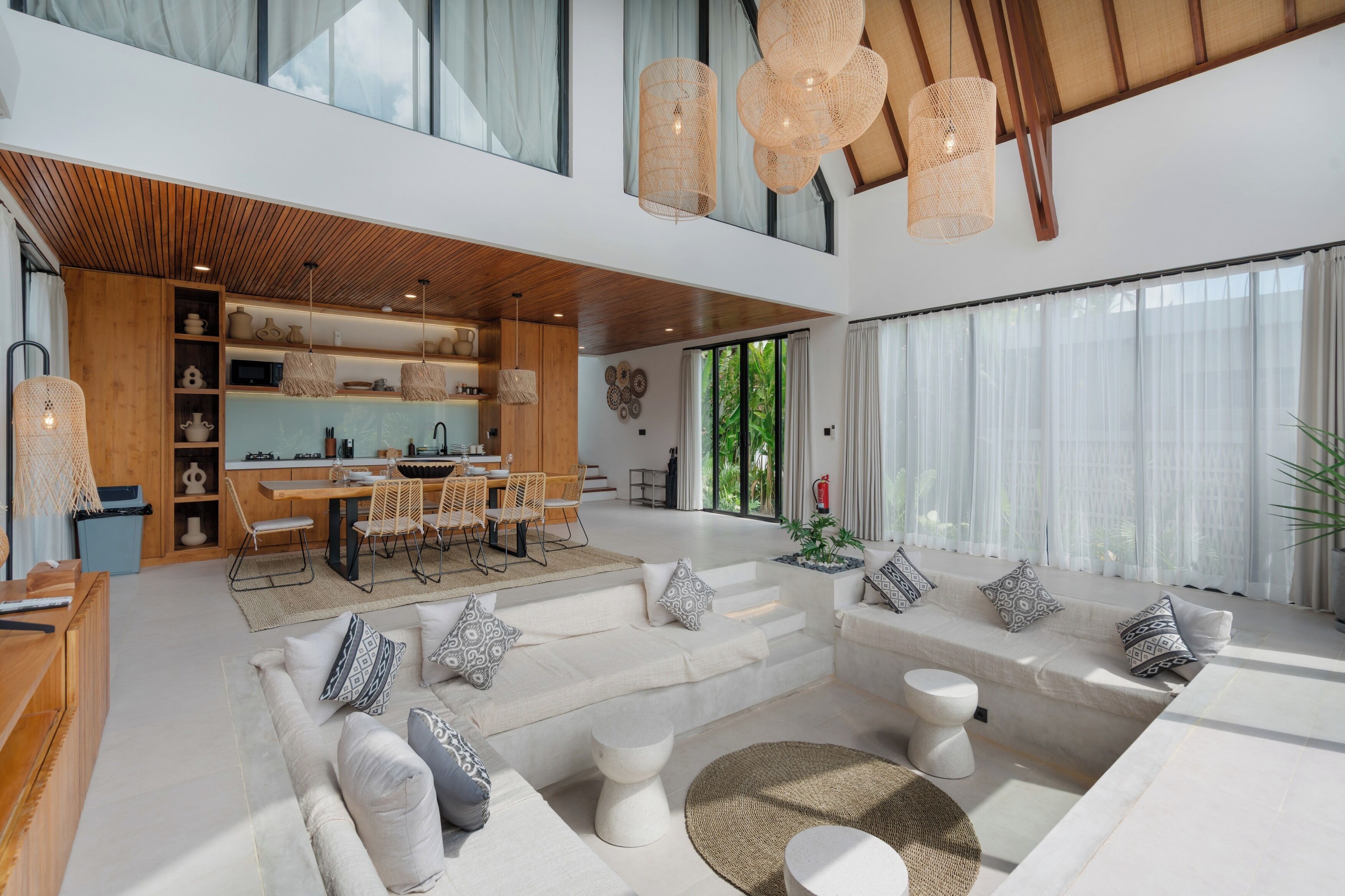 A spacious living area with a dining set, sofas, and a kitchen area with wooden cabinets and a built-in oven.
