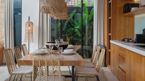Un comedor con mesa de madera, sillas de mimbre y una lámpara colgante.