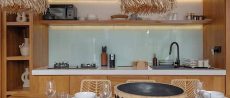 A modern kitchen with wooden cabinetry, a white countertop, and a large island with a black bowl.