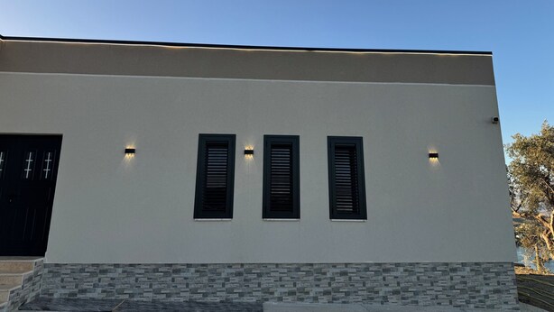A modern building with a flat roof, three windows with shutters, and a stone base. - The Lake Villa Tirana (Tiranë)