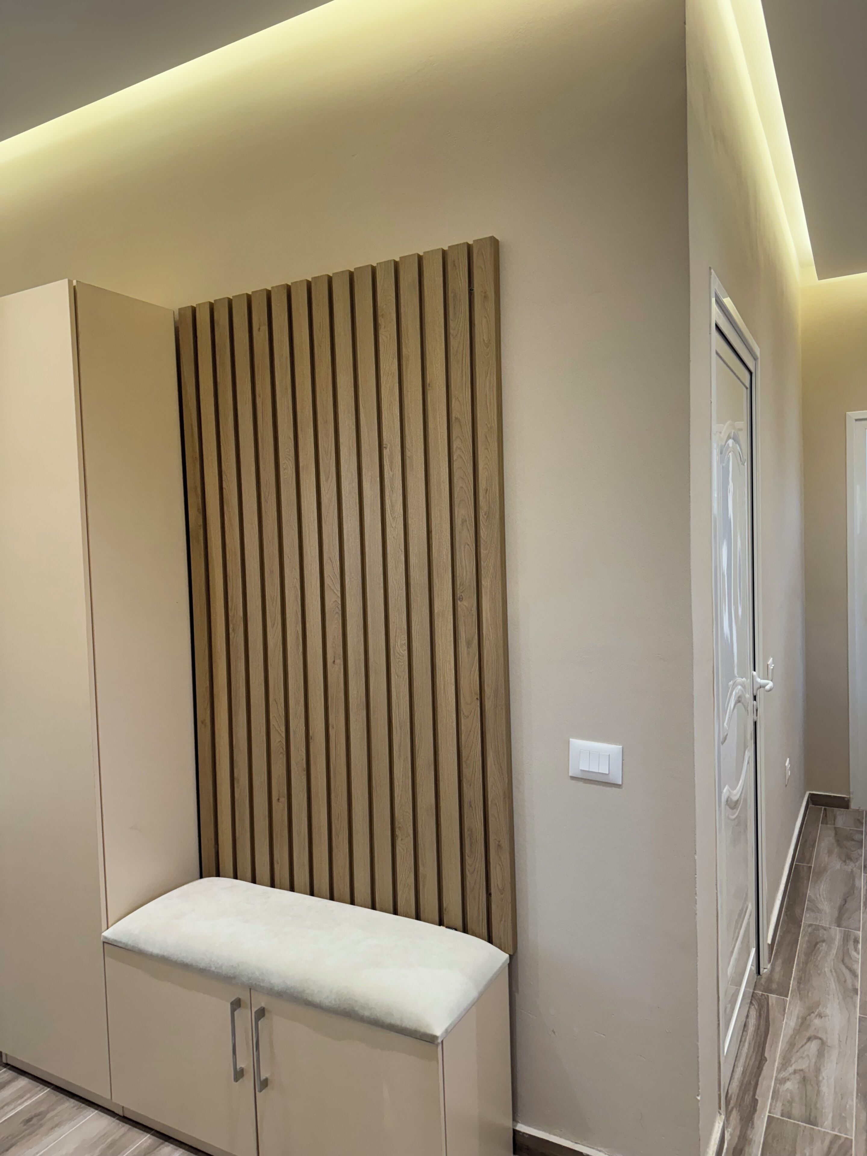 A modern interior with a built-in bench, a wooden slat wall, and a door with a glass panel.