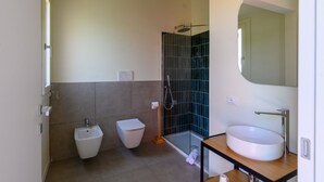 Ein modernes Badezimmer mit Bidet, Toilette, Duschkabine aus Glas und Waschbecken mit Spiegel.