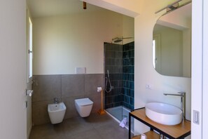 Ein modernes Badezimmer mit Bidet, Toilette, Duschkabine aus Glas und Waschbecken mit Spiegel.