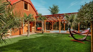 Ein Holzhaus mit rotem Dach, einer überdachten Veranda und einer Hängematte.